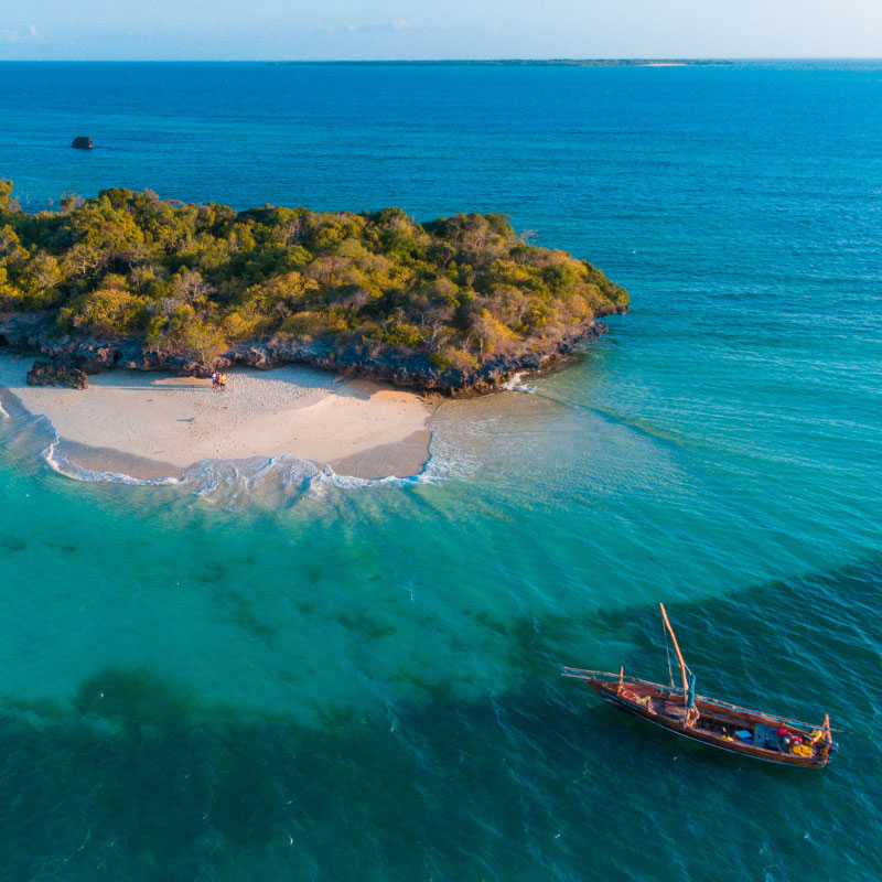 Zanzibar beach at sunset with a traditional dhow boat, the closing stop on a best Tanzania safaris itinerary